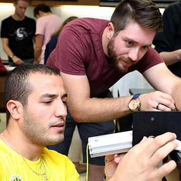 Two male students adjust the connections on an electrical project.